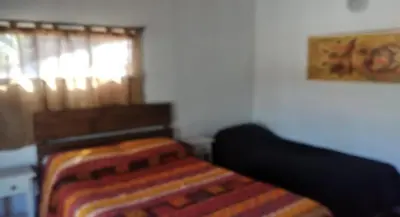 a bedroom with a bed with a blanket and a window at Cabaña Paulina in Santa Rosa de Calamuchita