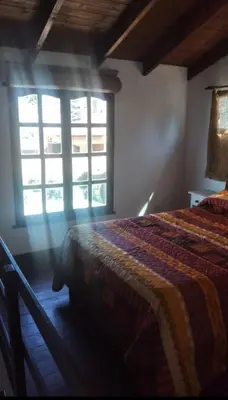 a bedroom with a bed and two windows at Cabaña Paulina in Santa Rosa de Calamuchita