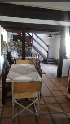 a table and chairs in a room with a stone wall at Cabaña Paulina in Santa Rosa de Calamuchita