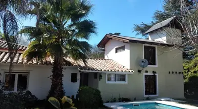 a house with a palm tree and a swimming pool at Cabaña Paulina in Santa Rosa de Calamuchita