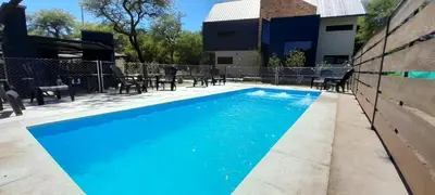 a swimming pool with blue water in front of a house at Laurentino Loft & Home in Villa General Belgrano