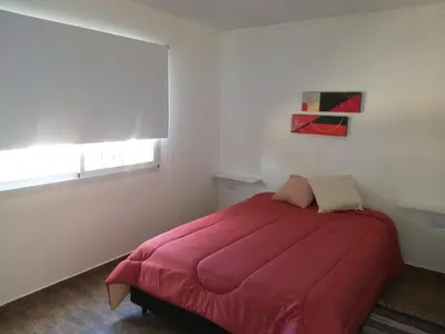 a bedroom with a red bed in a white room at Cabaña Los Pajaritos in Villa Rumipal