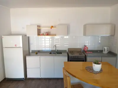 a kitchen with white appliances and a wooden table at Cabaña Los Pajaritos in Villa Rumipal