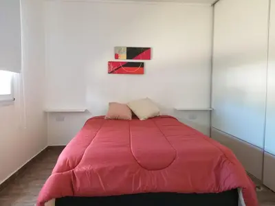 a bed with a pink comforter in a room at Cabaña Los Pajaritos in Villa Rumipal