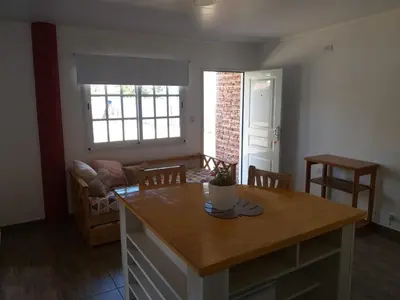 a kitchen with a table and a living room at Cabaña Los Pajaritos in Villa Rumipal