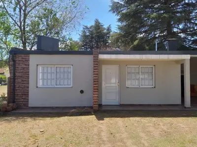 a small white house with a door and two windows at Cabaña Los Pajaritos in Villa Rumipal