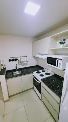 a white kitchen with a stove and a microwave at II Opera Towers Villa Carlos Paz in Villa Carlos Paz