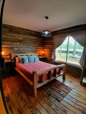 a bedroom with a large bed with a wooden wall at Cabañas LA IRMA in Villa Ciudad Parque