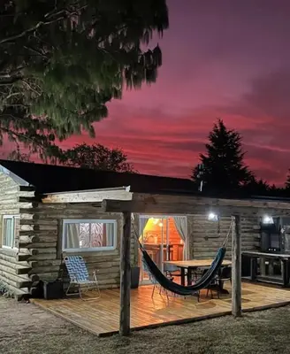 a log cabin with a hammock on a deck at Cabañas LA IRMA in Villa Ciudad Parque