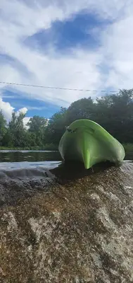 a green canoe sitting on the shore of a river at Cabañas Sol Marina in Villa Parque Siquiman