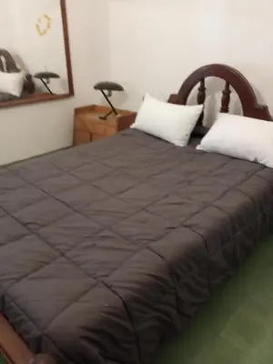a bed with a brown blanket and two white pillows at casa de marta a 50 mts del centro in Villa Carlos Paz