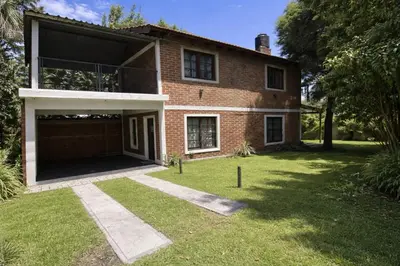 a brick house with a garage in the yard at Cabaña en el Centro de Mina Clavero in Mina Clavero