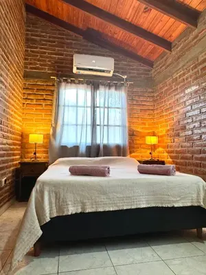a bedroom with a bed and a brick wall at Cabaña en el Centro de Mina Clavero in Mina Clavero