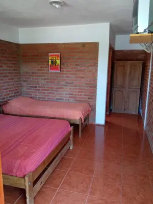 two beds in a room with a brick wall at Hostería Reserva Serrana in Mina Clavero
