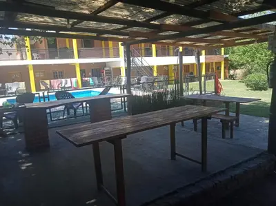 two picnic tables under a pavilion with a pool at Hostería Reserva Serrana in Mina Clavero