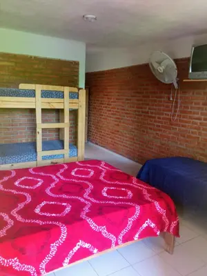 a bedroom with a red blanket on a bed at Hostería Reserva Serrana in Mina Clavero