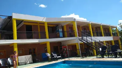 a woman standing in front of a house with a swimming pool at Hostería Reserva Serrana in Mina Clavero