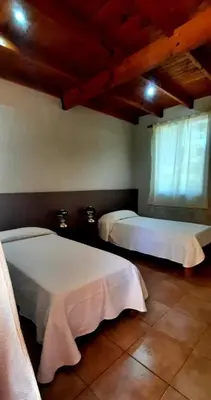 a bedroom with two beds with white sheets and a window at Posada Tanti El Durazno in Tanti
