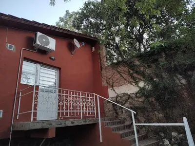 a red house with a balcony next to a building at Complejo Los Manantiales in Alta Gracia
