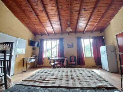 a room with a bed and a table and windows at Complejo Los Manantiales in Alta Gracia