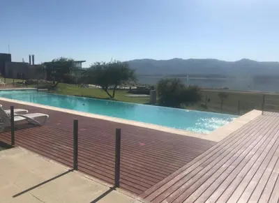 a large swimming pool with a wooden deck at Villa General Belgrano - Puerto del Águila in Potrero de Garay