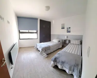 a white room with two beds and a television at Complejo Dos Osos in Villa General Belgrano