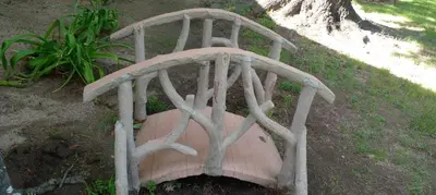 a wooden chair sitting on the ground in the grass at Cabaña en quinta la aurora in Mina Clavero