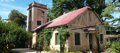 an old building with a red roof and a tower at Cabaña en quinta la aurora in Mina Clavero