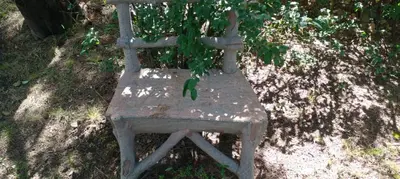 an old wooden chair sitting in the grass at Cabaña en quinta la aurora in Mina Clavero