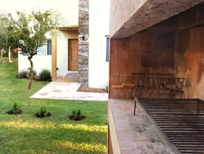 a building with a bench next to a yard at Morada del Cóndor - Cabañas Serranas in Merlo