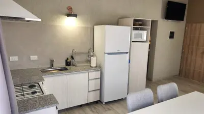 a kitchen with a white refrigerator and a sink at Morada del Cóndor - Cabañas Serranas in Merlo