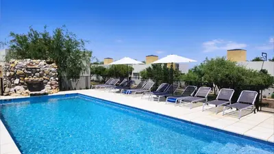 a pool with chairs and umbrellas on a patio at Morada del Cóndor - Cabañas Serranas in Merlo