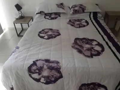 a bed with a blanket with flowers on it at Casa frente al lago en barrio privado in Almafuerte