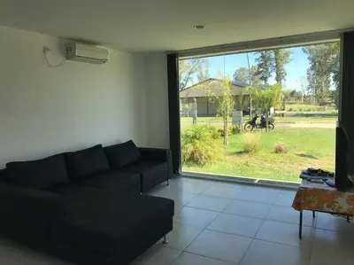 a living room with a couch and a large window at Casa frente al lago en barrio privado in Almafuerte