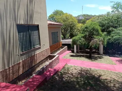 a house with a pink sidewalk next to a building at ESTANCIA VIEJA (CARLOS PAZ) in Estancia Vieja