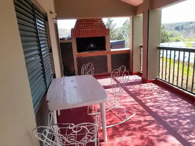 a porch with a table and chairs on a balcony at ESTANCIA VIEJA (CARLOS PAZ) in Estancia Vieja