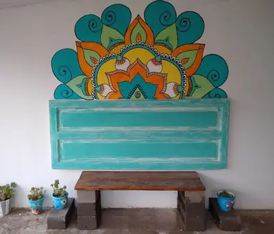 a bench sitting in front of a wall with a painting at Hospedaje El Ciruelo in Alta Gracia