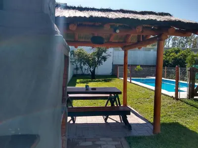 a picnic table under a gazebo next to a pool at Hospedaje El Ciruelo in Alta Gracia