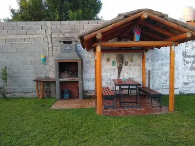a wooden pavilion with a table in a yard at Hospedaje El Ciruelo in Alta Gracia