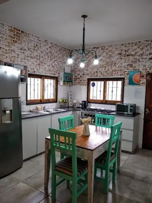 a kitchen with a wooden table and green chairs at Hospedaje El Ciruelo in Alta Gracia