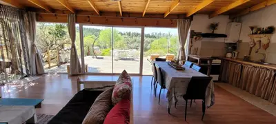 a living room with a table and a large window at Bela Vista Casa Serrana, Golpe de Agua in Los Reartes