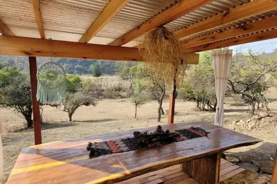 a wooden table under a roof with a view of the desert at Bela Vista Casa Serrana, Golpe de Agua in Los Reartes