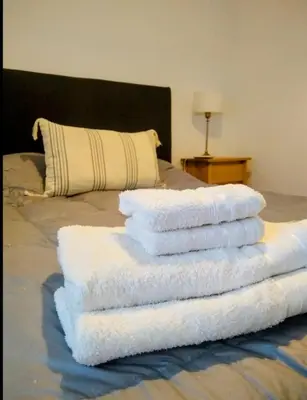 a stack of white towels on a bed at Departamento a estrenar con piscina con cochera opcional in Río Cuarto