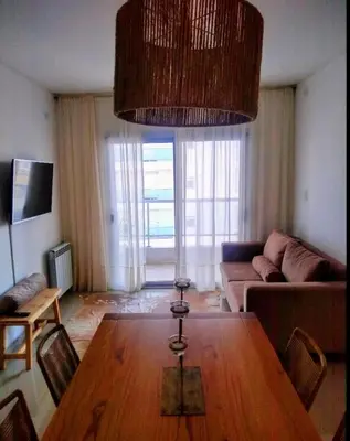 a living room with a wooden table and a couch at Departamento a estrenar con piscina con cochera opcional in Río Cuarto
