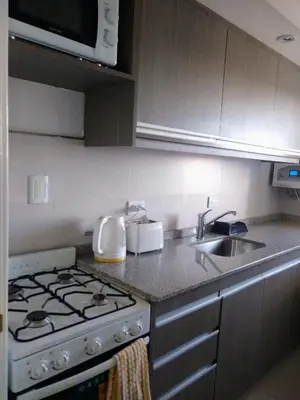 a kitchen with a stove and a sink at Departamento a estrenar con piscina con cochera opcional in Río Cuarto