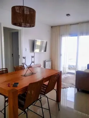 a dining room with a wooden table and chairs at Departamento a estrenar con piscina con cochera opcional in Río Cuarto