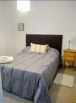 a bed with a blue comforter in a bedroom at Departamento a estrenar con piscina con cochera opcional in Río Cuarto