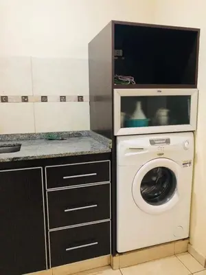 a kitchen with a washing machine and a microwave at Departamento zona Nuevocentro Shopping in Cordoba