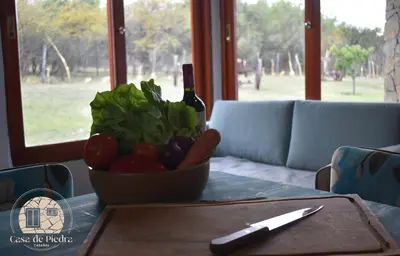 a bowl of vegetables on a table with a bottle of wine at Cabañas Casa de Piedra Los Molles - San Luis in Los Molles