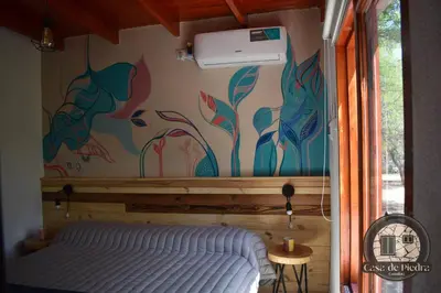 a bedroom with a bed and a painting on the wall at Cabañas Casa de Piedra Los Molles - San Luis in Los Molles
